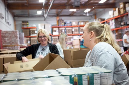 LAVIDGE IMPACT committee members RuthAnn Hogue and Melanee Arnett fold boxes for St. Mary's Food Bank Alliance.
